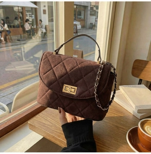 Close-up of brown quilted suede handbag with gold turn-lock and chain strap detail