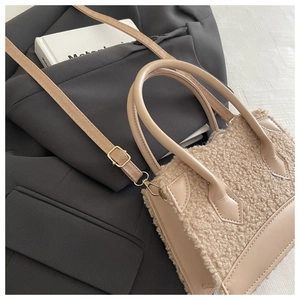 Détail du petit sac en laine d'agneau beige sur blazer gris avec bandoulière réglable