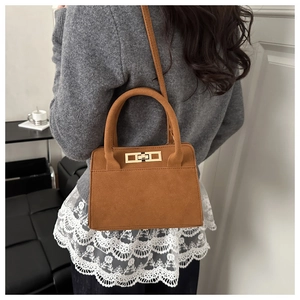Dettaglio di borsa vintage in pelle scamosciata marrone con fibbia dorata e manico
