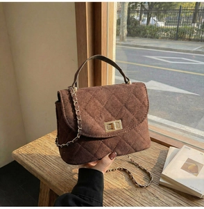 Close-up of quilted dark brown suede handbag featuring a gold metal twist lock and chain strap