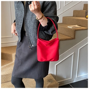 Détail du sac hobo en nylon rouge montrant le logo de la marque sur surface lisse