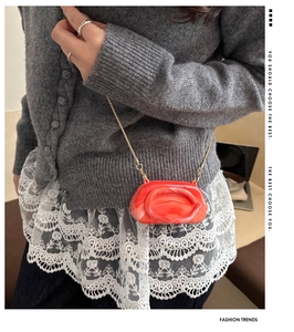 Detail of red marble acrylic mini bag with gold chain strap on a model shoulder