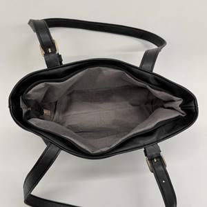 Minimalist black leather tote bag with large capacity and adjustable gold buckle straps