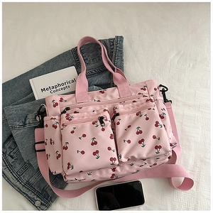 Gros plan d'un sac cabas à imprimé cerise rose avec poches avant et large bandoulière