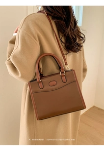 Borsa a mano retrò in pelle marrone indossata da una modella con un cappotto kaki