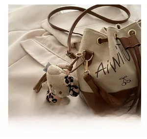 Detail view of velvet bucket bag with drawstring closure and cute plush bear charm