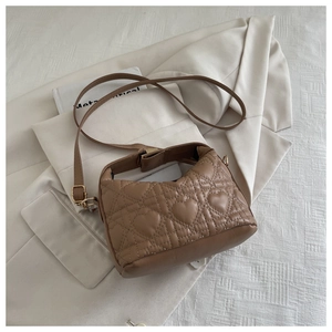 Detailed close-up of brown heart-quilted PU leather bag with golden zipper and strap