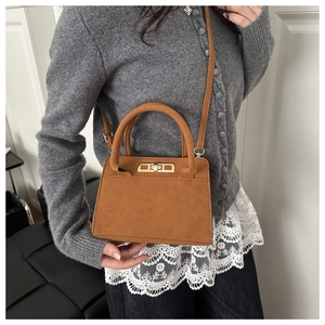 Vue détaillée du sac bandoulière en daim marron avec fermoir pivotant en métal doré
