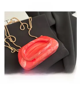 Detail of red and white marbled acrylic clutch with elegant gold chain strap