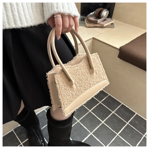 Detail of beige faux shearling handbag showing textured plush fabric and sleek PU leather trim