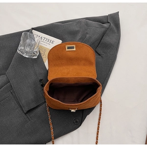 Detail view of the brown suede crossbody bag with metal twist lock and gold chain strap