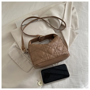 Brown heart-quilted crossbody bag detail with gold hardware and smartphone for size scale
