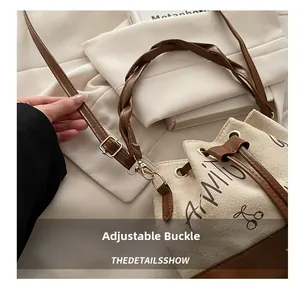Detail showing the adjustable gold metal buckle on the brown leather strap of the bucket bag