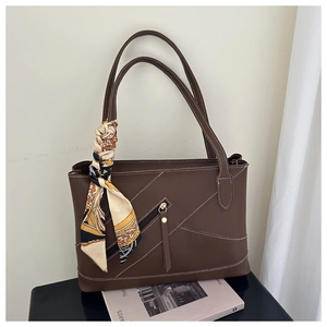 Detailopname van de koffiebruine leren tote bag met luxe zijden sjaal aan het handvat