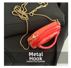 Macro shot of orange marble pattern acrylic bag with golden metal chain and hook detail