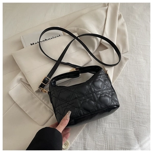 Detail of black leather crossbody bag featuring heart quilting and gold hardware