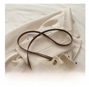Detail of adjustable brown leather shoulder strap on a beige suede bucket bag