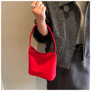Sac seau minimaliste rouge en nylon porté avec une veste et une jupe longue