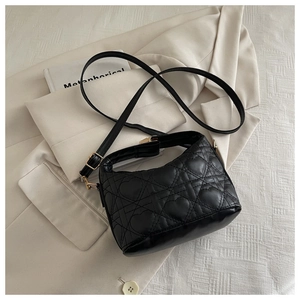 Detail of black heart-quilted leather texture and golden metal strap buckle on bag