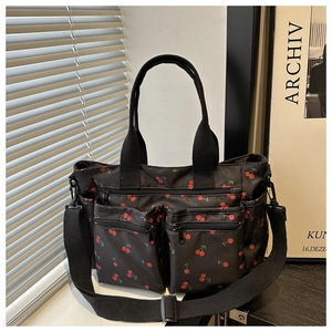 Détail du sac cabas noir en toile à motif cerises avec poches avant zippées pratiques