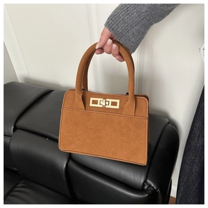 Détail d'un sac à main en daim marron avec un fermoir rotatif rectangulaire en métal doré