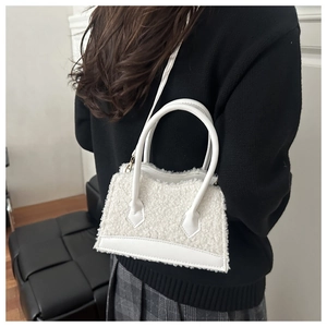 Sac à main blanc en fausse fourrure porté par un mannequin en pull noir et jupe grise