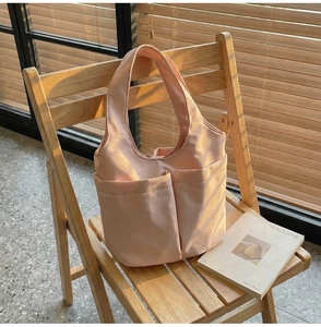 Détail du sac cabas en nylon rose clair avec deux poches avant sur une chaise