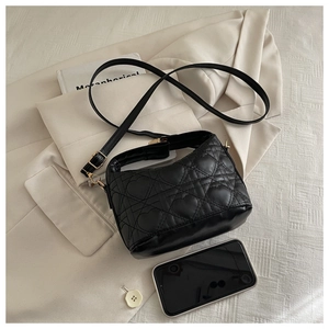 Detail of black heart-quilted hobo bag with gold clasp shown on a blazer background