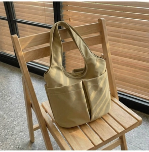 Détail du sac seau en nylon kaki avec deux poches frontales et ombres naturelles