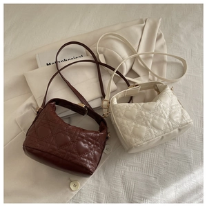 Detail of heart-quilted texture on brown and white leather shoulder bags with gold buckles