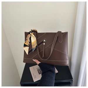 Detail of coffee brown leather tote bag with white stitching and decorative silk scarf