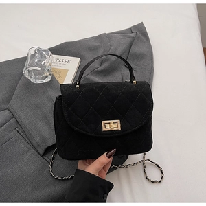 Close-up of black quilted suede handbag with gold turn-lock and elegant chain strap