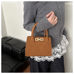 Detail of a brown suede handbag with a golden clasp lock and textured matte finish