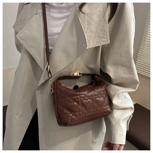 Detail of heart-shaped quilted stitching on luxury dark brown crossbody handbag