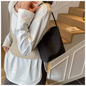 Sac bandoulière chic en nylon noir porté avec une tenue minimaliste en intérieur