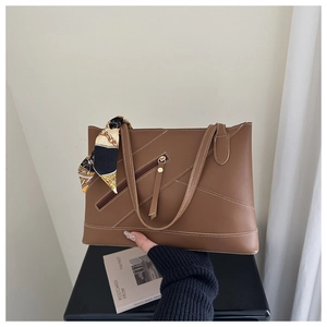 Detail of dark brown tote bag with contrast stitching and decorative silk scarf
