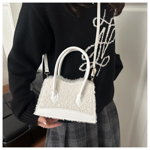 Detail of white faux fur crossbody bag with golden hardware and leather handles