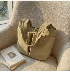 Gros plan d'un sac seau en nylon kaki avec bandoulière large sous une lumière naturelle