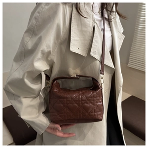 Detail of heart-shaped quilted pattern on brown leather bag with gold hardware
