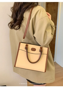 Vista dettagliata della borsa beige retrò con bordi marroni e toppa ovale decorativa