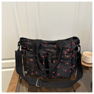 Détail d'un sac cabas noir avec imprimé cerise et multiples poches zippées