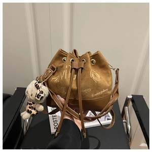 Detail of vintage brown suede bucket bag with text print and plush dog charm