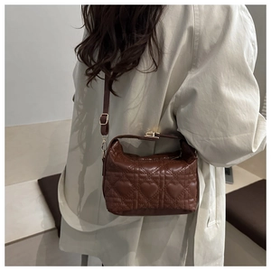 Detail of dark brown quilted crossbody bag featuring heart pattern and gold metal buckle