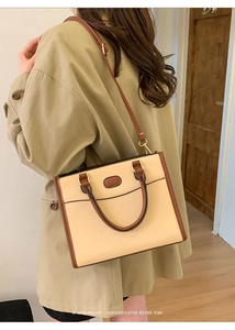 Dettaglio di una borsa tote bicolore minimalista indossata con un trench kaki