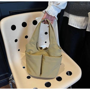 Détail d'un sac seau en nylon vert clair avec poches avant et poignée robuste intégrée