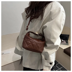 Detail of dark brown heart-quilted leather bag with golden clasp and adjustable strap