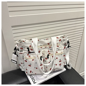 Détail du sac cabas en toile blanche avec imprimés cerises et poches zippées avant