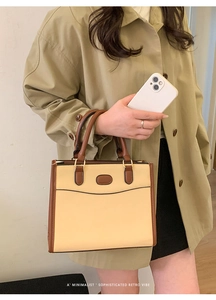 Dettaglio di una borsa a mano retrò minimalista beige con bordo marrone indossata da modella