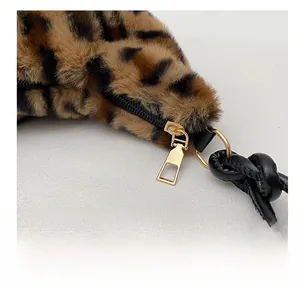 Dettaglio borsa leopardata con cerniera dorata e manico in pelle nera con nodo decorativo