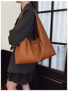 Caramel brown large capacity tote bag worn on shoulder over dark gray suit blazer